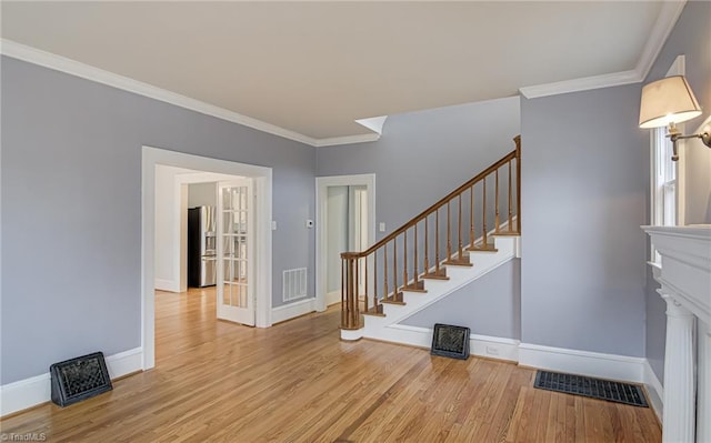 staircase with visible vents, ornamental molding, and wood finished floors