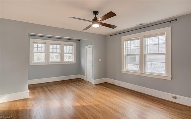 empty room with visible vents, baseboards, a ceiling fan, and light wood finished floors