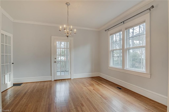 unfurnished room featuring baseboards, visible vents, an inviting chandelier, ornamental molding, and hardwood / wood-style flooring