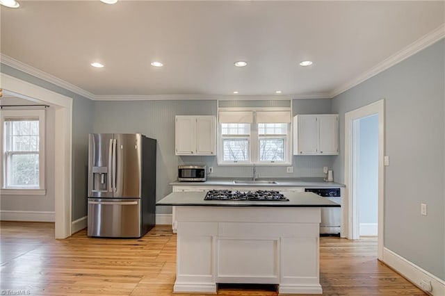 kitchen with a sink, stainless steel appliances, crown molding, and white cabinetry