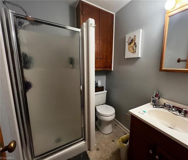 bathroom featuring tile patterned flooring, vanity, toilet, and a shower with shower door