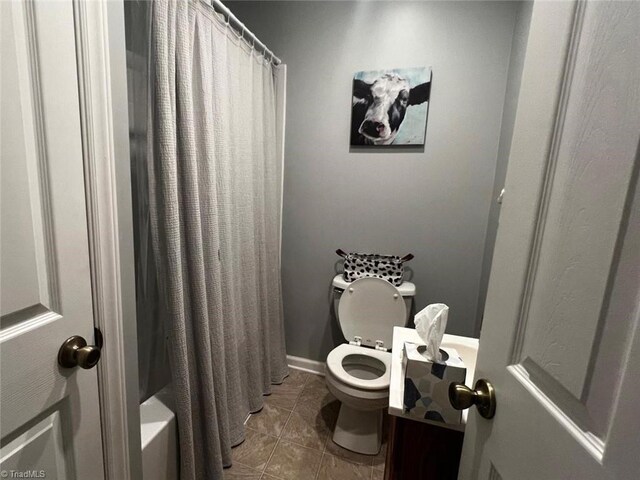 bathroom featuring tile patterned floors, toilet, and shower / bath combo with shower curtain