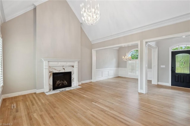 unfurnished living room with a chandelier, a fireplace, light wood-style floors, ornamental molding, and a high ceiling