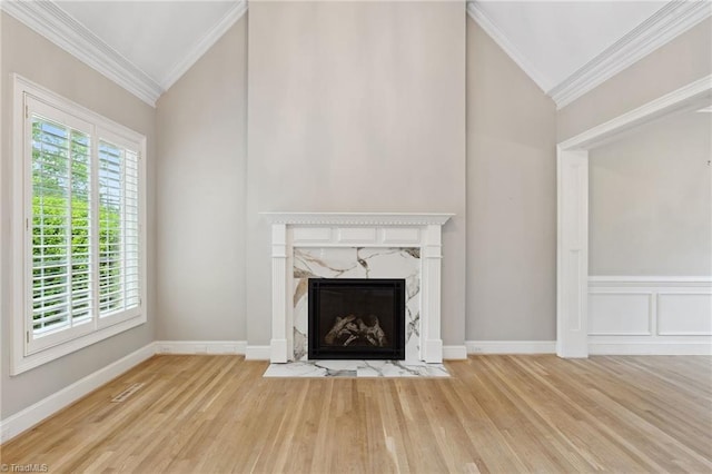 unfurnished living room with ornamental molding, a premium fireplace, wood finished floors, vaulted ceiling, and baseboards
