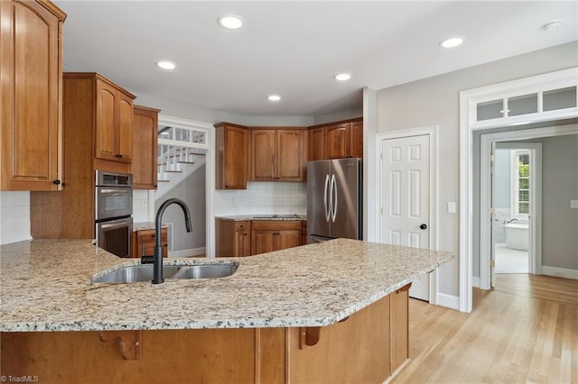 kitchen with stainless steel appliances, a sink, a peninsula, a kitchen breakfast bar, and backsplash