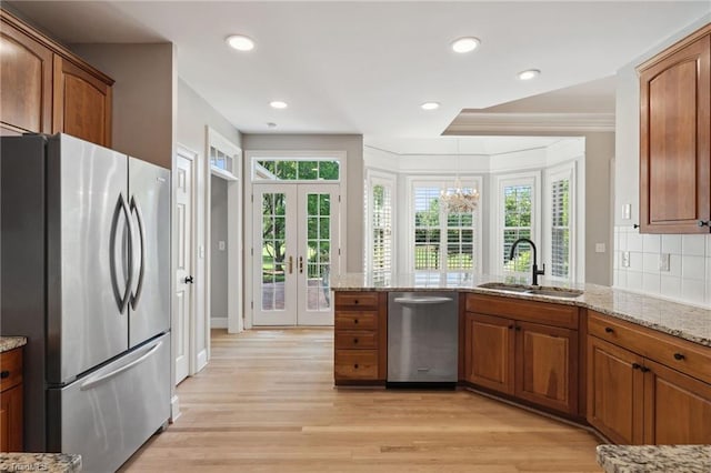 kitchen with stainless steel appliances, a sink, plenty of natural light, brown cabinetry, and recessed lighting