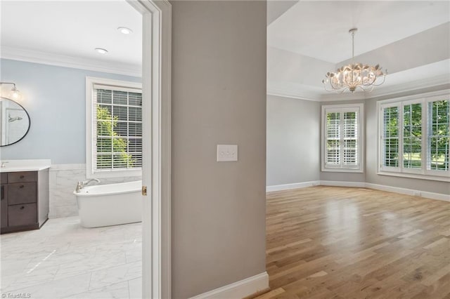 bathroom with ornamental molding, healthy amount of natural light, vanity, a freestanding bath, and a chandelier
