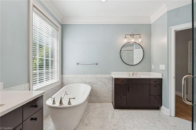 full bathroom with a freestanding bath, two vanities, marble look tiles, crown molding, and wainscoting