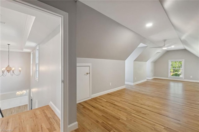 additional living space with light wood finished floors, a chandelier, baseboards, and lofted ceiling