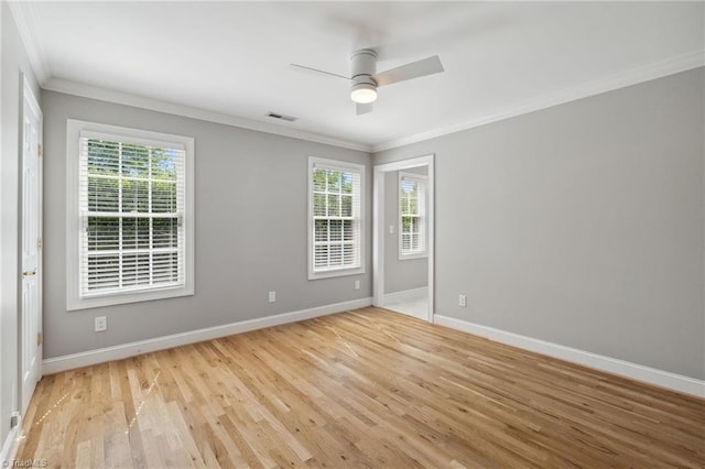 empty room featuring crown molding, plenty of natural light, baseboards, and light wood finished floors