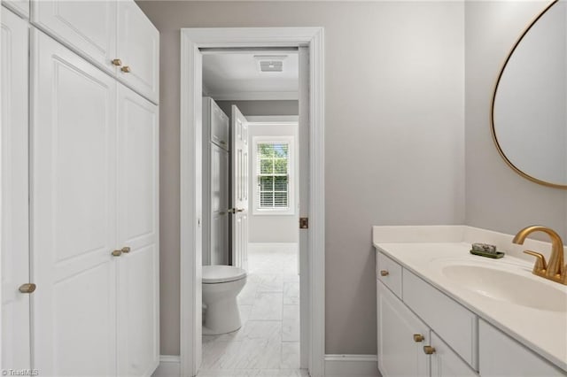 bathroom with marble finish flooring, baseboards, vanity, toilet, and crown molding