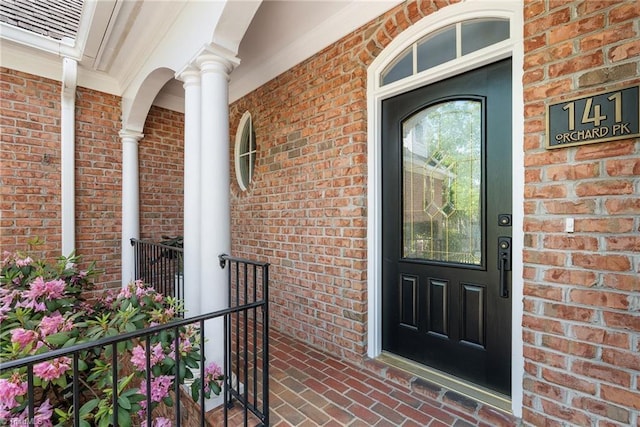 doorway to property featuring brick siding and covered porch