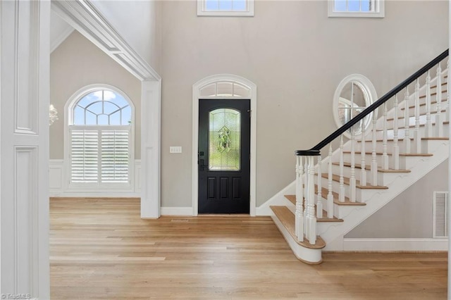 entrance foyer featuring stairs, wood finished floors, and a high ceiling