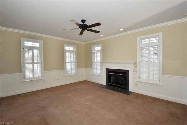 unfurnished living room featuring carpet floors, a fireplace with flush hearth, ornamental molding, and wainscoting