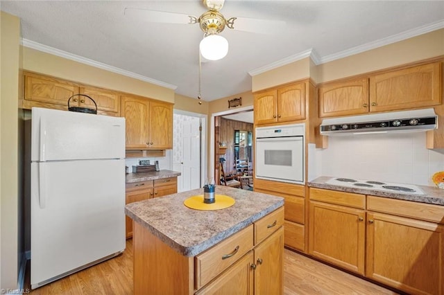 kitchen featuring under cabinet range hood, crown molding, a kitchen island, light wood-style flooring, and white appliances