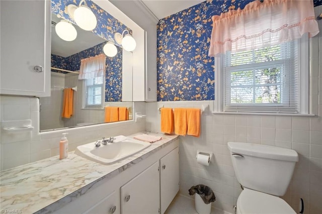 bathroom featuring wallpapered walls, a shower with shower curtain, a wainscoted wall, toilet, and vanity