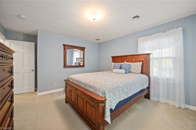 bedroom with baseboards, visible vents, light carpet, and a textured ceiling