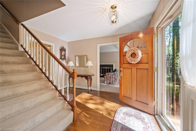 foyer with wood finished floors, baseboards, and stairs