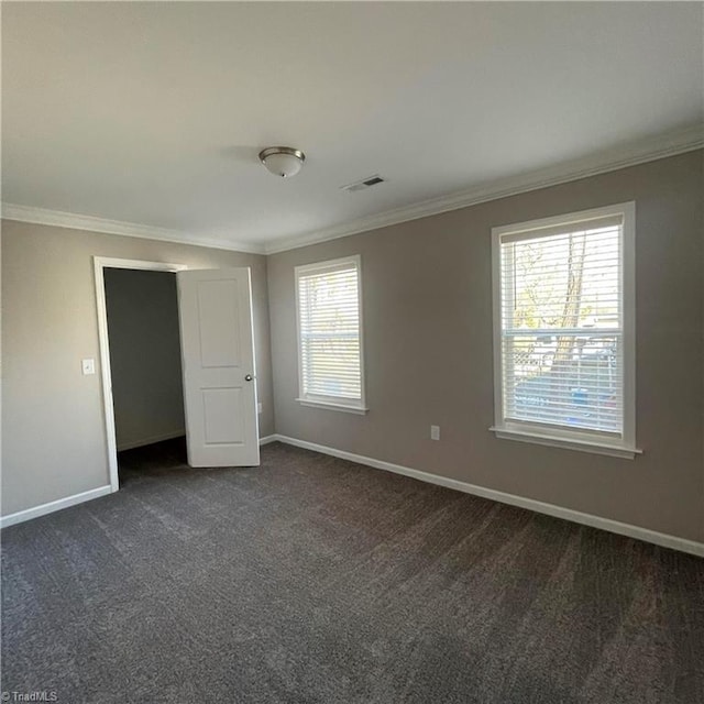 unfurnished bedroom with dark colored carpet and crown molding