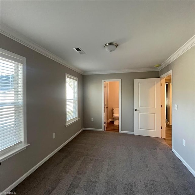 unfurnished bedroom featuring ensuite bathroom, dark carpet, and ornamental molding