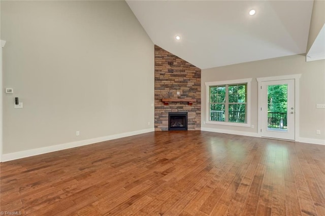 unfurnished living room with high vaulted ceiling, wood-type flooring, and a stone fireplace