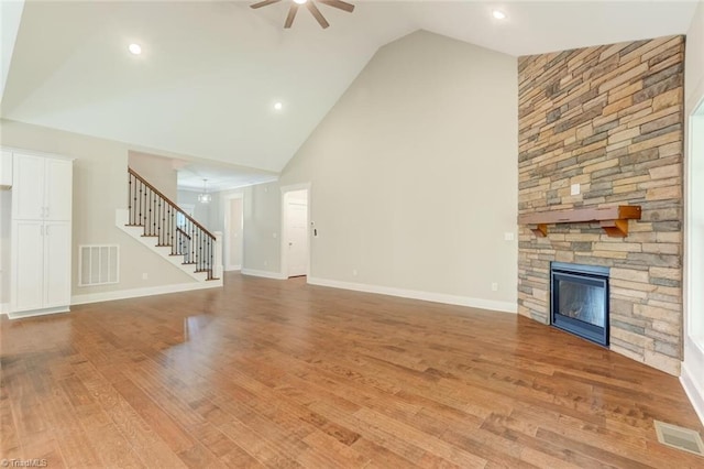 unfurnished living room featuring a fireplace, high vaulted ceiling, light hardwood / wood-style flooring, and ceiling fan