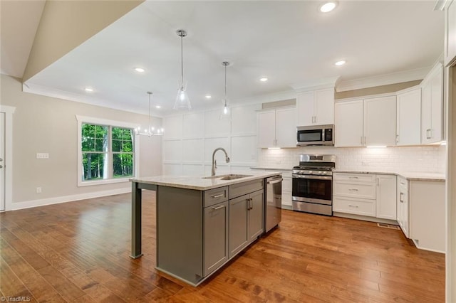 kitchen with gray cabinetry, appliances with stainless steel finishes, white cabinetry, sink, and an island with sink