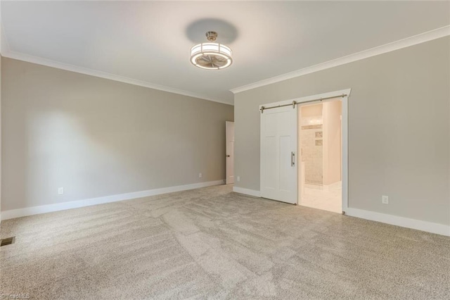 unfurnished bedroom featuring crown molding, light colored carpet, and a barn door