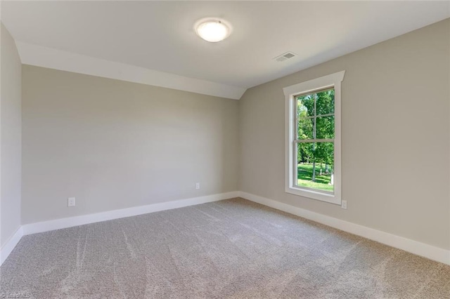 spare room featuring carpet flooring and vaulted ceiling