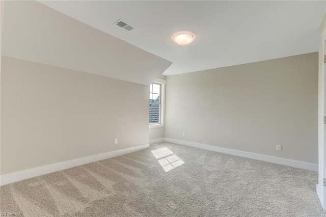 spare room featuring lofted ceiling and light carpet