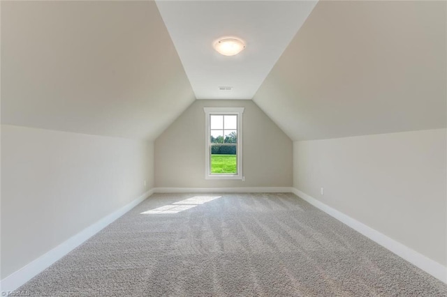 additional living space with light colored carpet and vaulted ceiling