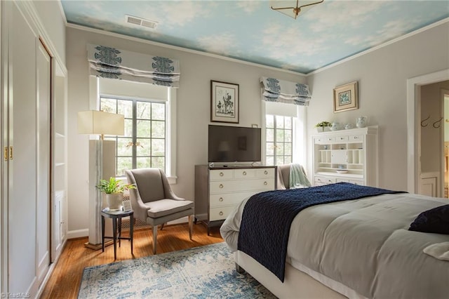 bedroom with light wood-type flooring, multiple windows, and crown molding