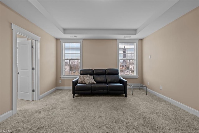 living area featuring a tray ceiling and light carpet