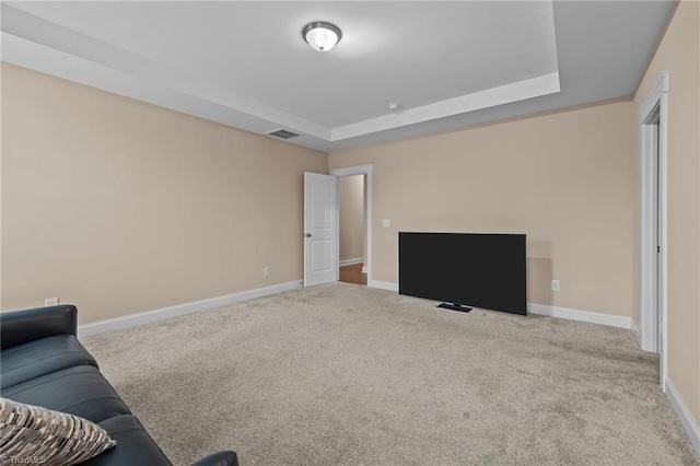 living room with a raised ceiling and light colored carpet