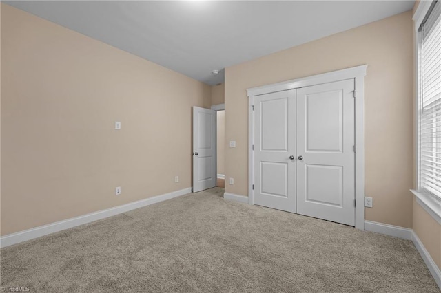 unfurnished bedroom with light colored carpet and a closet