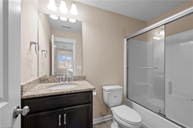 full bathroom with tile patterned floors, vanity, toilet, and bath / shower combo with glass door