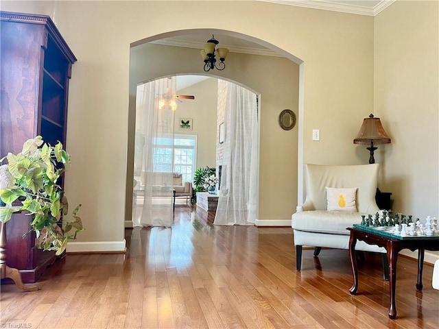 living area with baseboards, arched walkways, ornamental molding, and hardwood / wood-style flooring