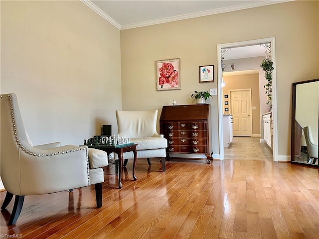 living area featuring baseboards, ornamental molding, and light wood finished floors