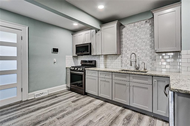 kitchen with stainless steel appliances, a sink, and gray cabinetry