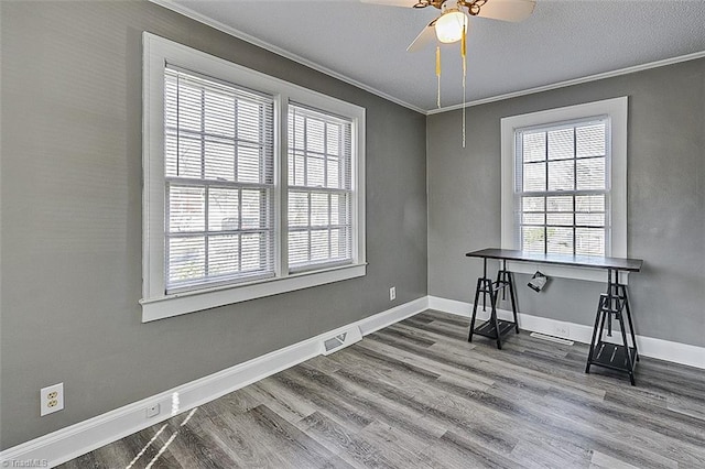 office space with ornamental molding, visible vents, baseboards, and wood finished floors