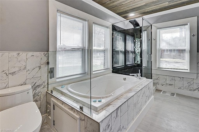 full bath with a garden tub, tile walls, visible vents, toilet, and a stall shower