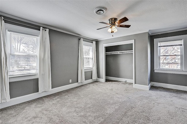 unfurnished bedroom featuring a closet, ornamental molding, carpet flooring, a textured ceiling, and baseboards