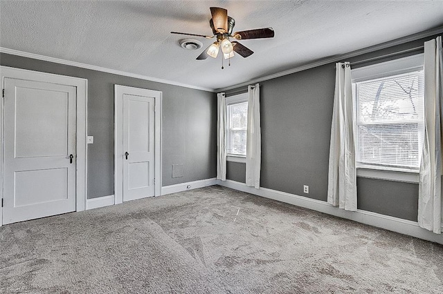 carpeted empty room with crown molding, visible vents, ceiling fan, a textured ceiling, and baseboards