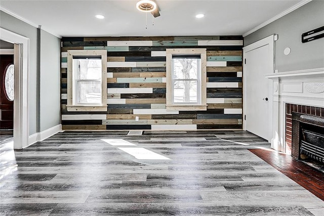 unfurnished living room with a brick fireplace, crown molding, baseboards, and wood finished floors