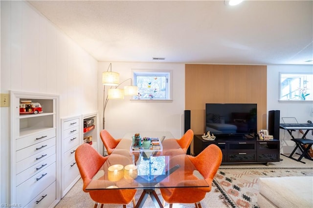 carpeted dining space with wood walls and plenty of natural light