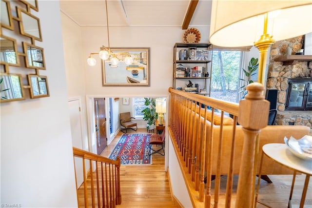 hallway with an inviting chandelier, beam ceiling, and light wood-type flooring