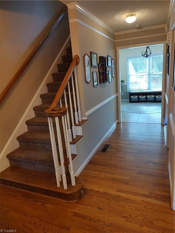 3210 Clamoor Dr, Winston-Salem, NC 27127 - stairway featuring crown molding, wood finished floors, a chandelier, and a textured ceiling