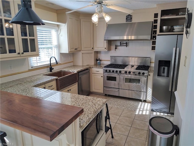 3210 Clamoor Dr, Winston-Salem, NC 27127 - kitchen featuring stainless steel appliances, wall chimney exhaust hood, ceiling fan, ornamental molding, and glass insert cabinets