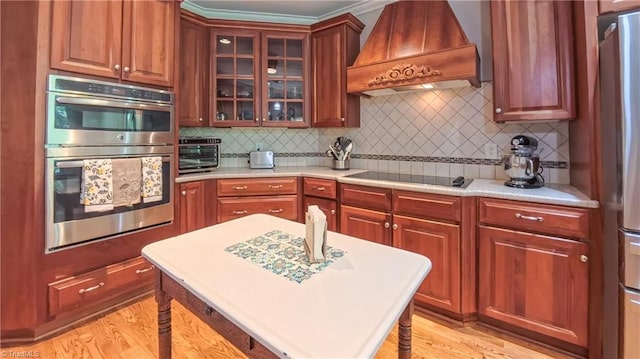 1250 Whitworth Ct, Kernersville, NC 27284 - kitchen featuring custom range hood, stainless steel appliances, light countertops, tasteful backsplash, and glass insert cabinets