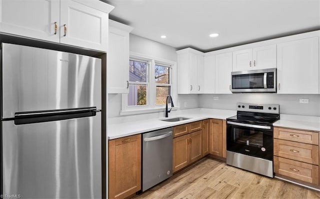 kitchen featuring light wood-type flooring, stainless steel appliances, sink, and white cabinets